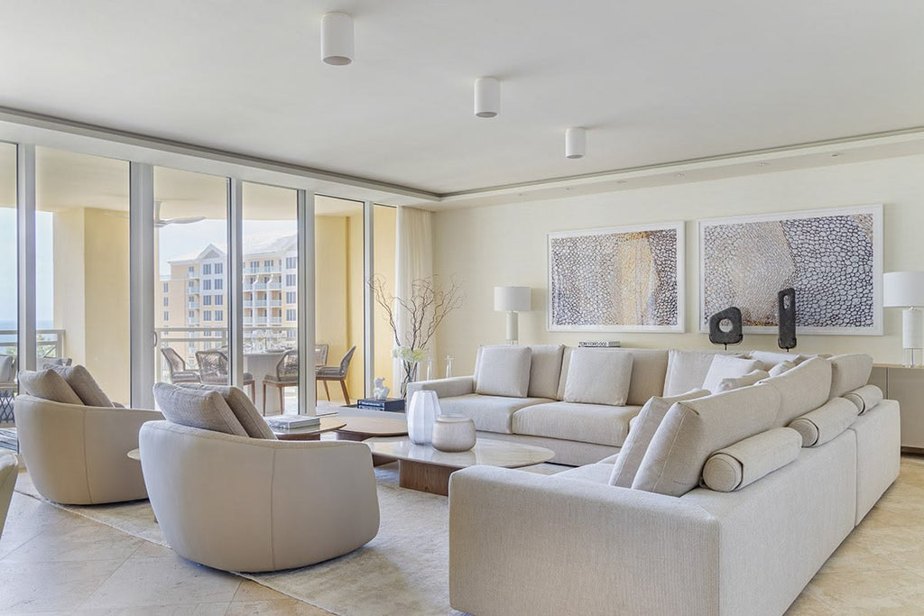 Modern living room with beige sofa, armchairs, and large windows.
